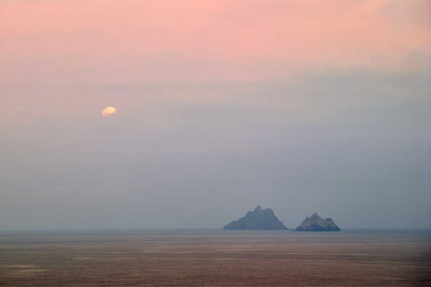 Moonset over the Skellig Islands at dawn with pink and blue sky reflected on calm sea, Kerry