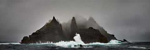 Small Skellig island rising from the Atlantic with jagged cliffs, mist, and seabirds circling, Kerry