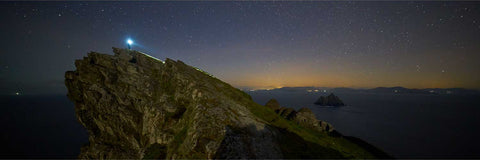 A lone figure with a light ascending the ancient steps to the monastery on Skellig Michael at night