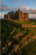 Aerial vertical view of the Rock of Cashel at sunset, medieval ruins catching golden light on the Tipperary plain