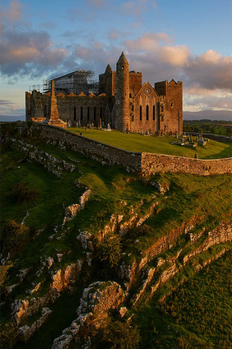 Aerial vertical view of the Rock of Cashel at sunset, medieval ruins catching golden light on the Tipperary plain