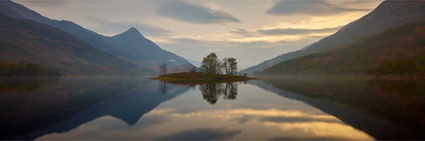 Sunset over Loch Leven with the Pap of Glencoe reflected in calm water and trees along the shore, Scottish Highlands