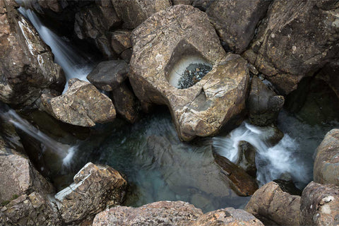 Crystal-clear cascading waterfalls flowing over layered rock formations at the Fairy Pools on the Isle of Skye, Scotland