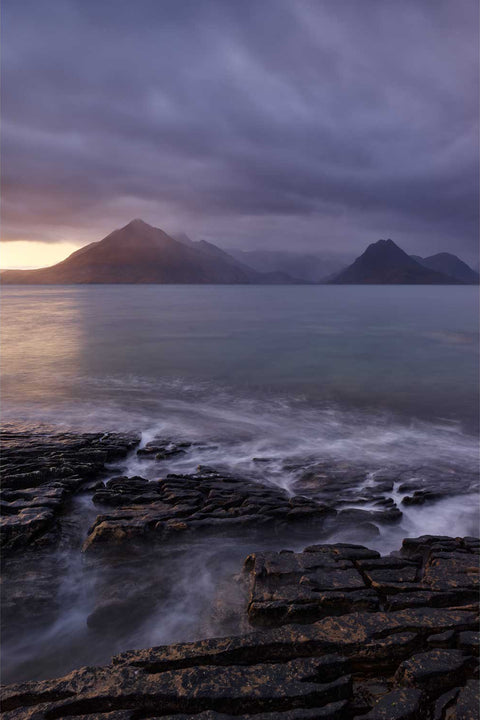Sunset squall over the Cuillin mountains seen from Elgol's rocky shore on the Isle of Skye with silky long exposure waves