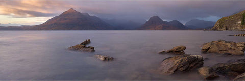 Panoramic sunset view of the Cuillin mountains from Elgol on the Isle of Skye with serene waters reflecting evening sky