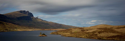 Panoramic view across dark Loch Fada toward the Old Man of Storr pinnacles on the Trotternish Ridge under heavy skies on Skye