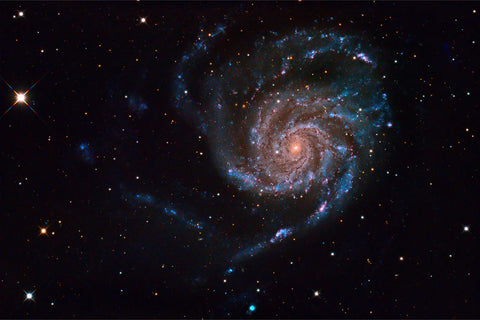 The Pinwheel Galaxy M101 with spiral arms glowing blue and pink against deep black space
