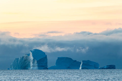 Massive icebergs under amber sky and low cloud, Scoresby Sound, Greenland, fine art landscape photograph by Peter Cox