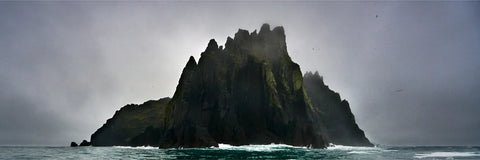 Inis Tuaisceart, the northernmost Blasket Island, rising sheer from the sea under heavy mist with jagged cliffs and seabirds circling