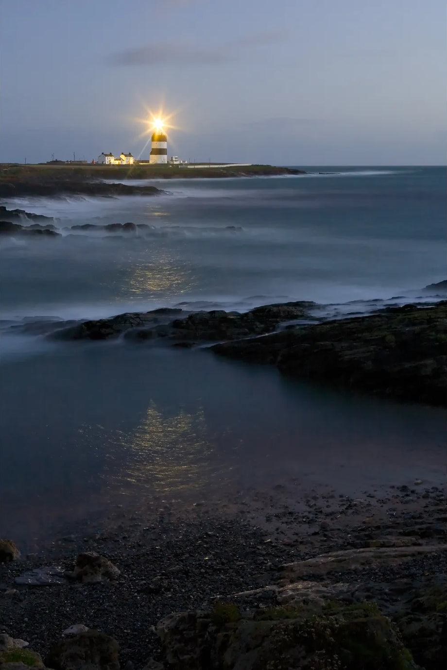 Hook Lighthouse beam reflecting across calm waters at dusk, Co. Wexford — fine art landscape photograph by Peter Cox