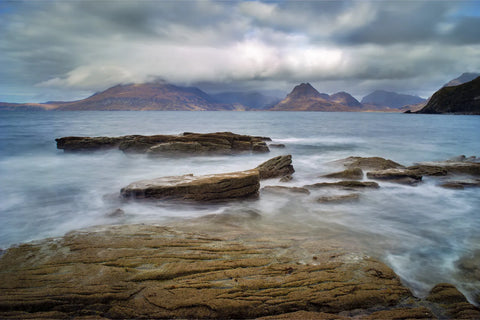 Long exposure seascape from Elgol on the Isle of Skye with the Black Cuillin mountains rising through cloud across smooth water